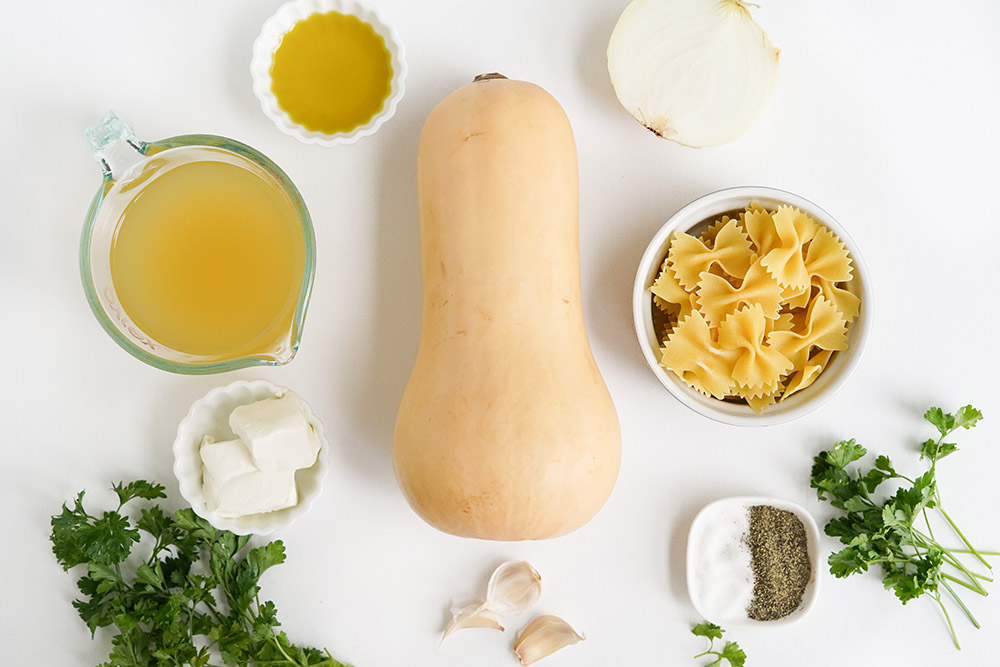 Butternut squash, pasta, and other ingredients to make soup on a table.