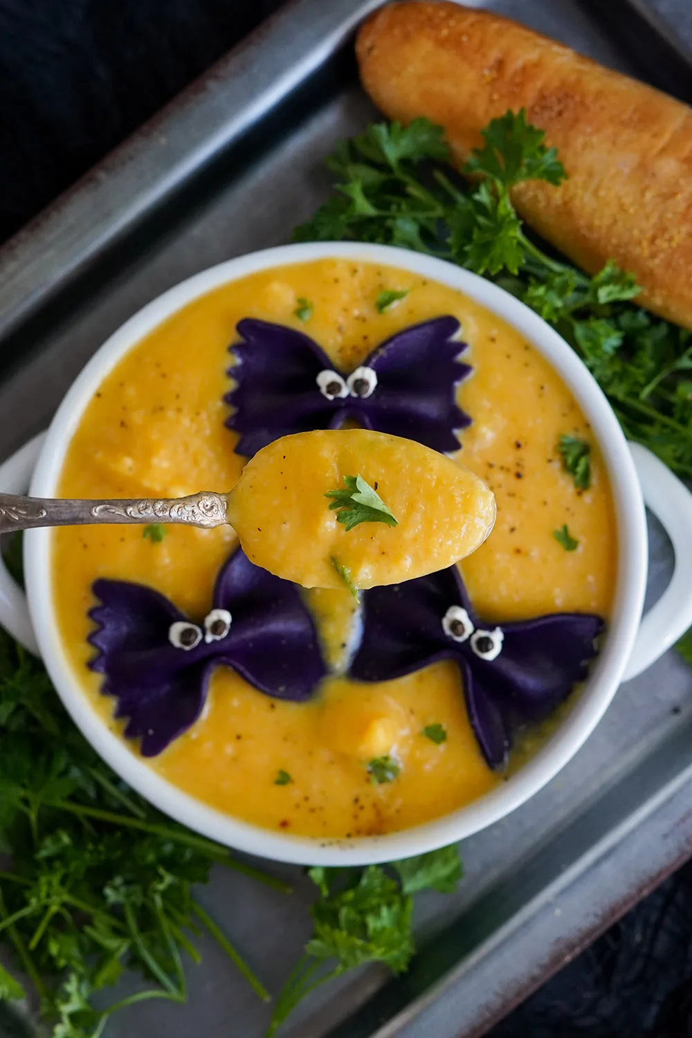 Spoon raised over bowl of Halloween butternut squash soup with pasta bats.