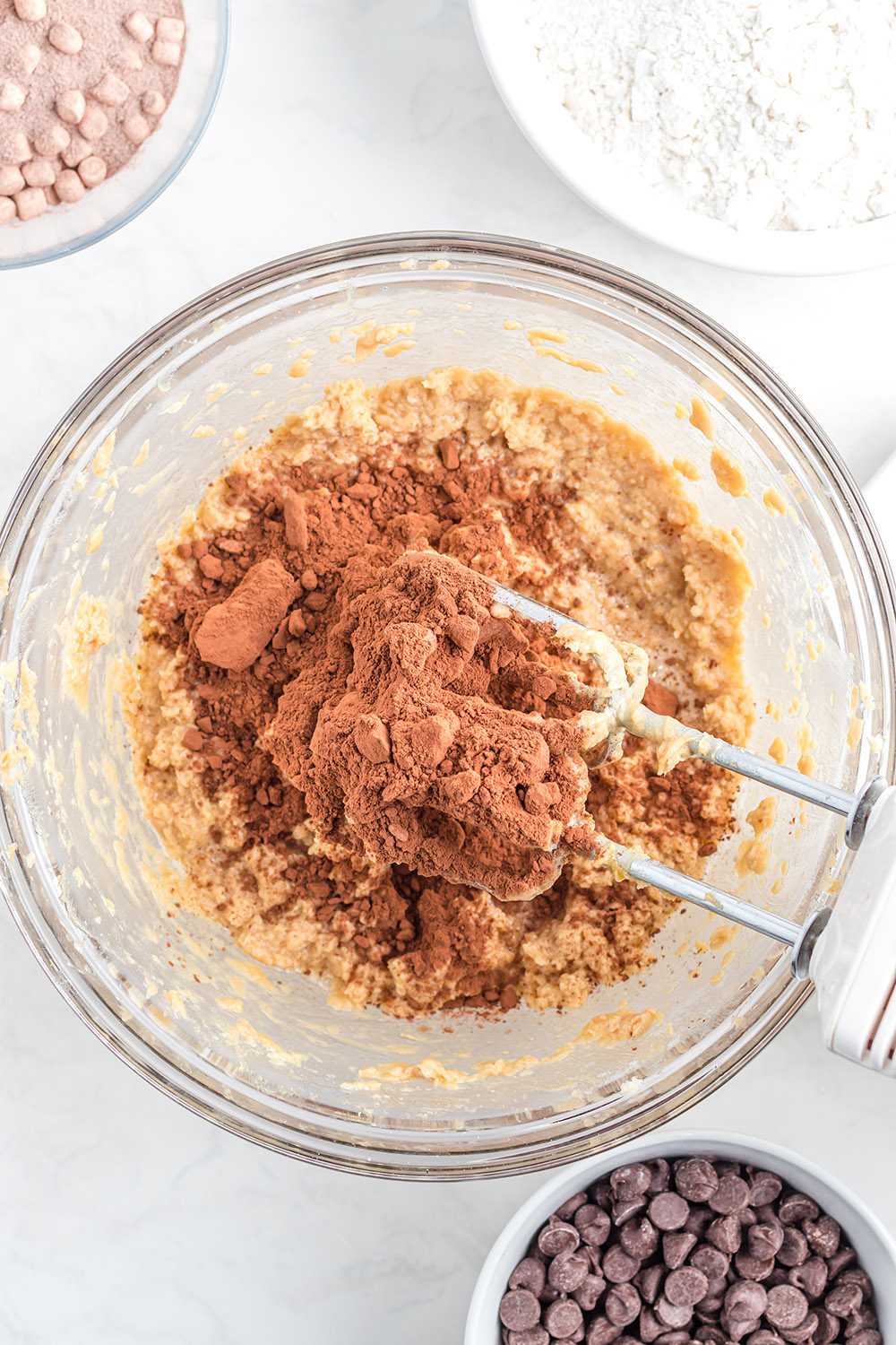 Cocoa powder added to batter in a bowl with a mixer.