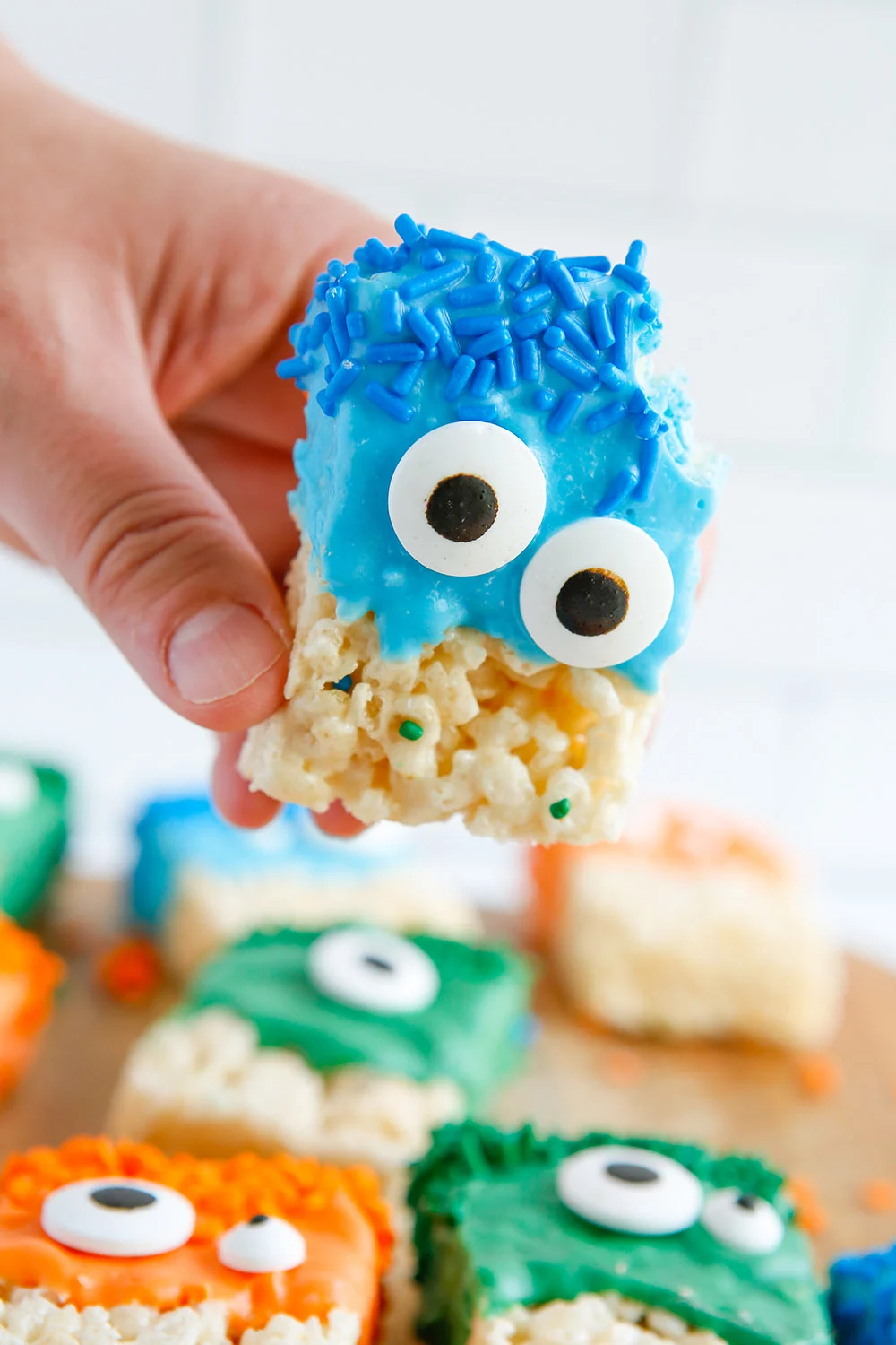 Holding a blue monster rice crispy treat with a bite taken out of it.