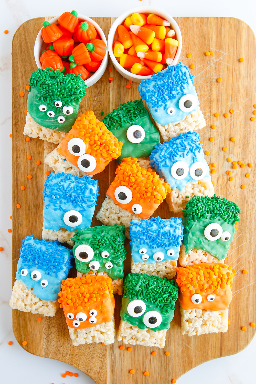 Several monster crispy rice treats on a cutting board.