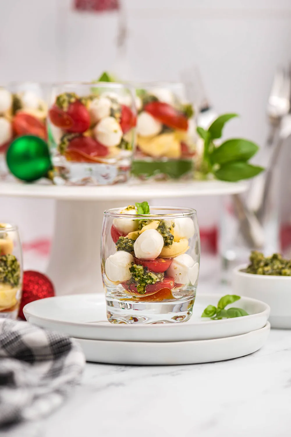 Glasses of caprese salad on a plate and on a serving dish. 