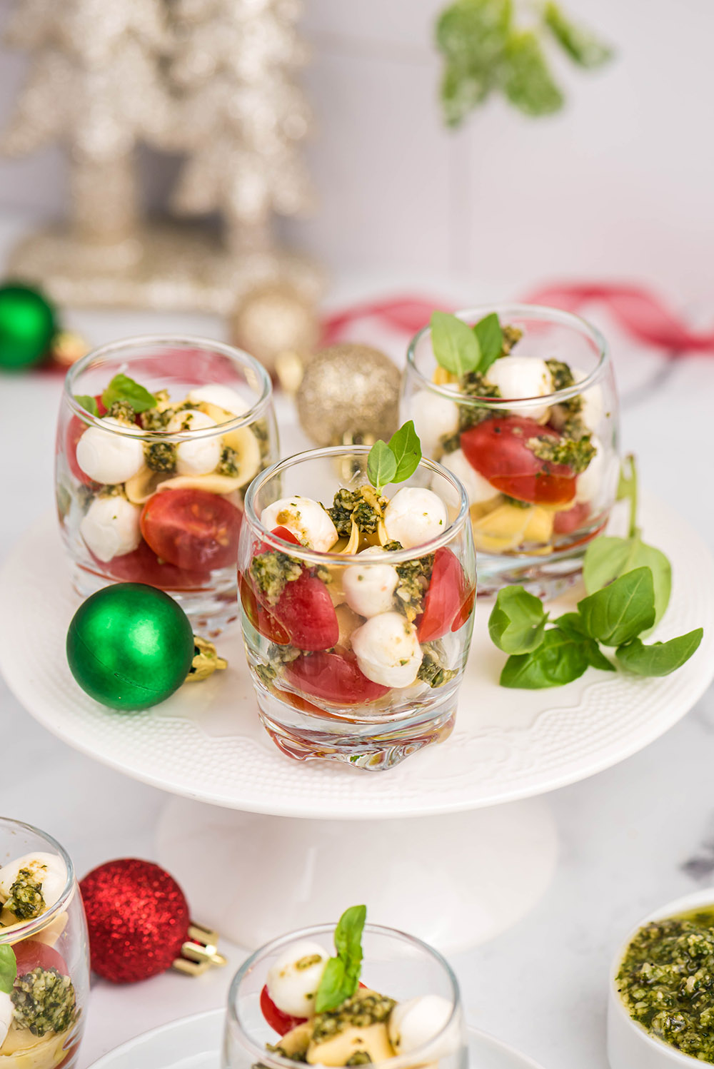Glasses of tomato, mozzarella, pesto salad with holiday ornaments on the table. 