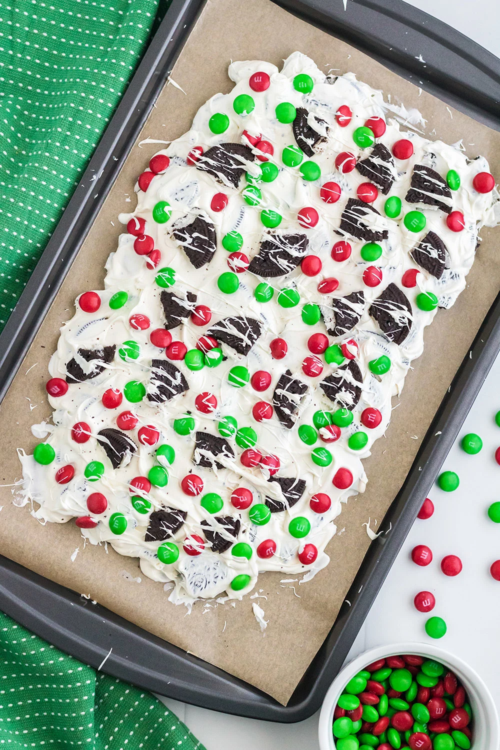 Oreo bark with red and green m&ms on a baking sheet. 