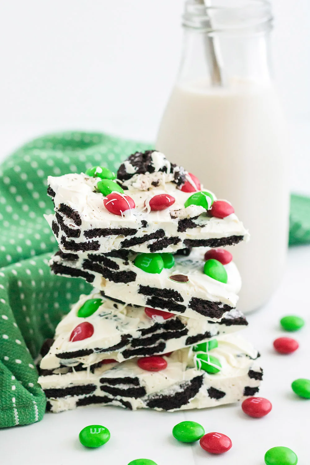 Stack of OREO bark next to a glass of milk and a green napkin. 