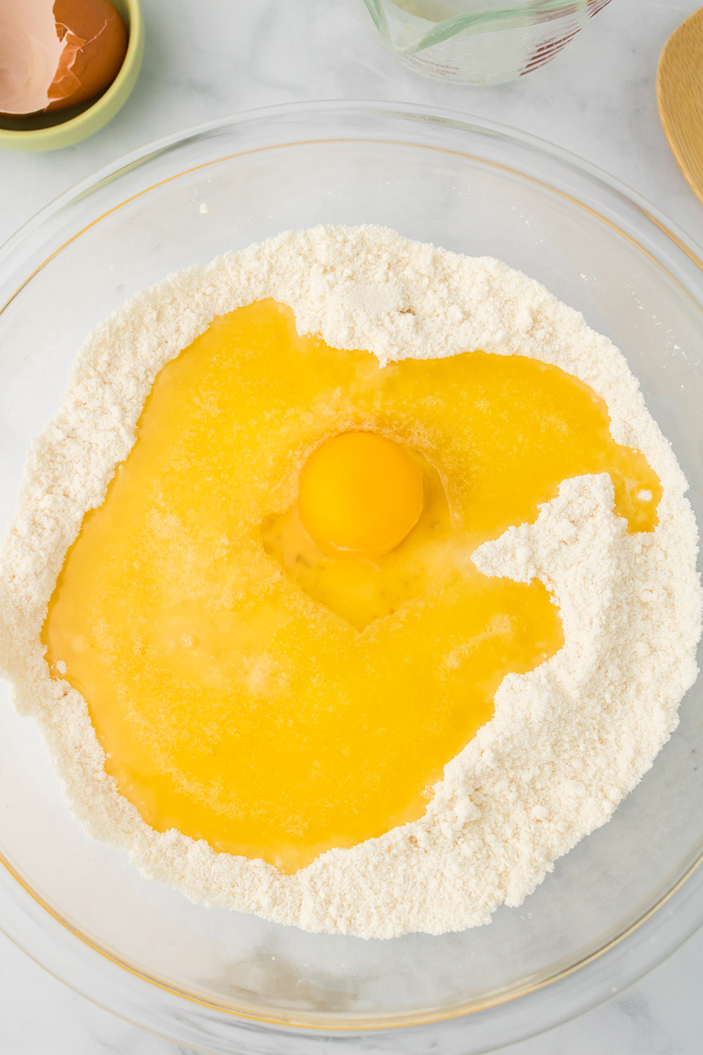 Egg on top of flour in a clear bowl. 