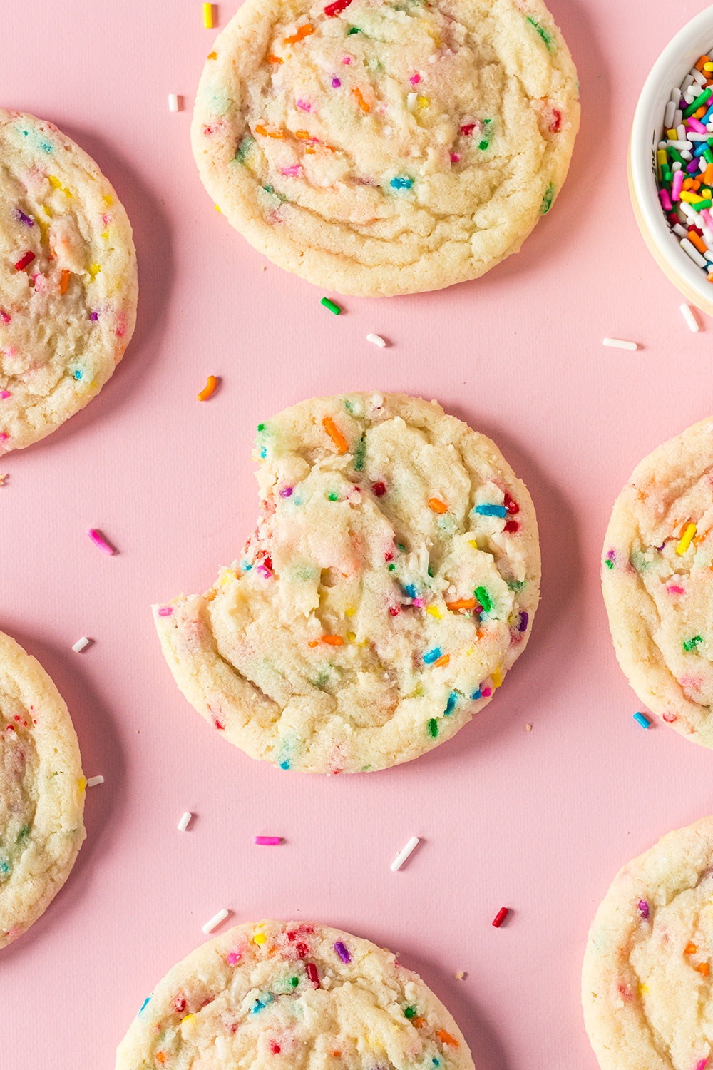 Funfetti cookies on a pink background with sprinkles. 