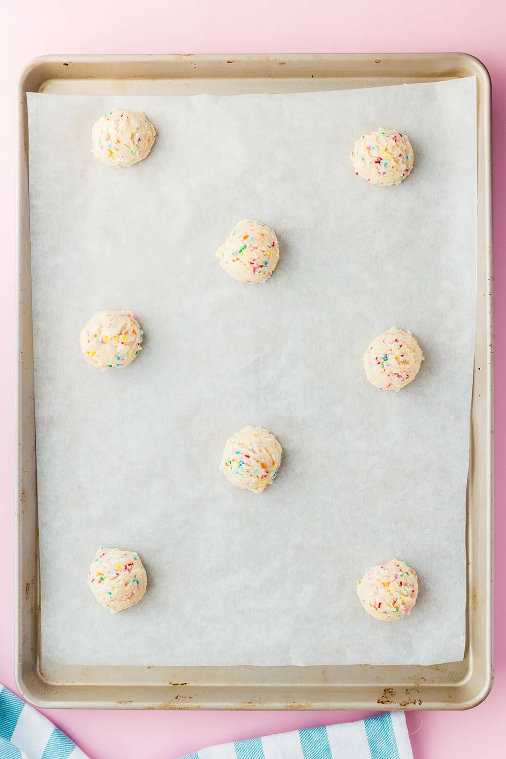 Cookie dough balls on a baking sheet with parchment paper. 