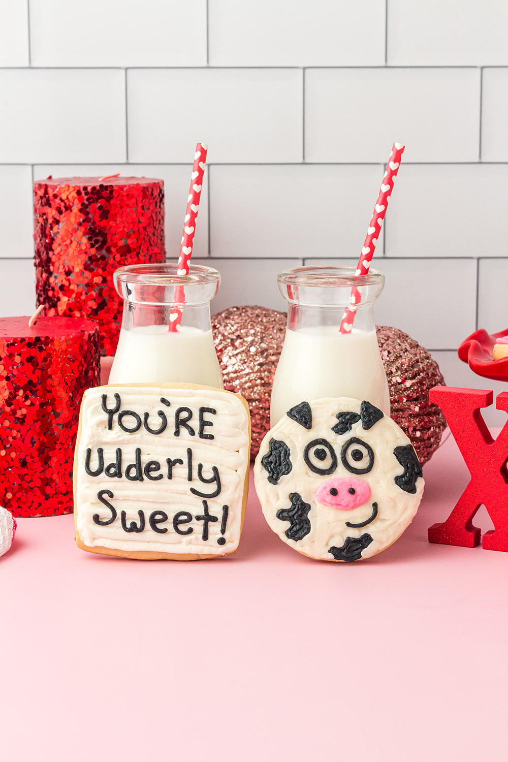 You're Udderly Sweet and a cow Valentine's themed cookies next to milk on a table. 