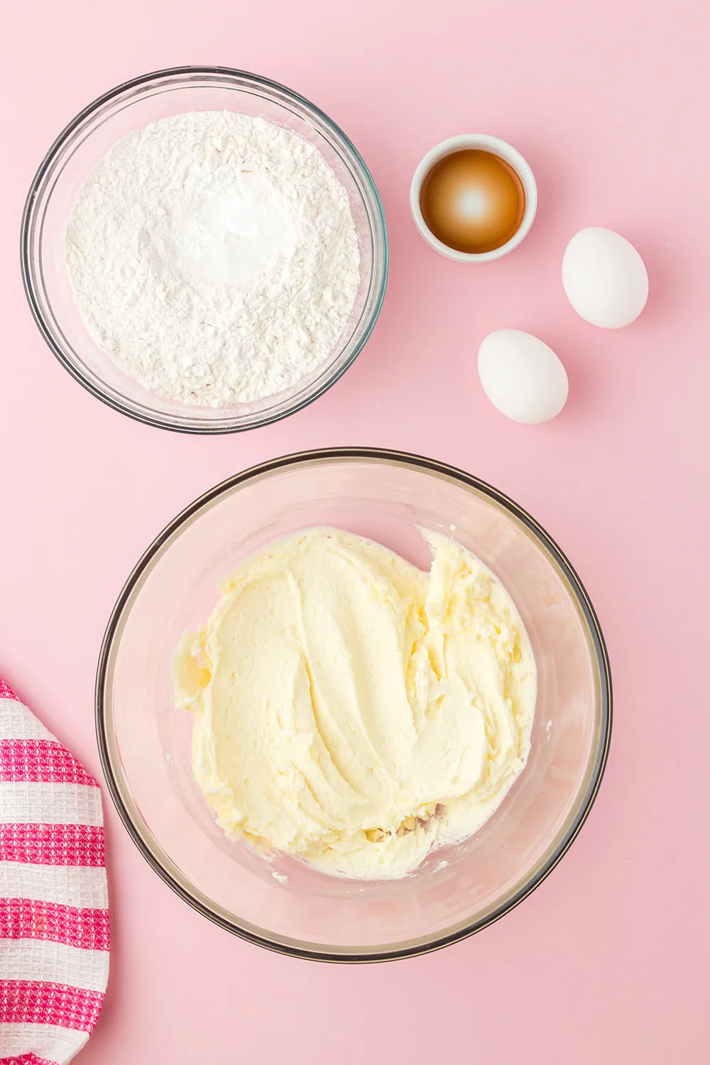 Eggs, vanilla, and powdered sugar next to bowl of dough. 