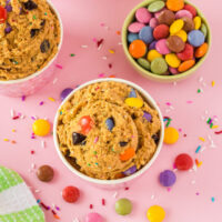 Overhead image of monster cookie dough in cups with candy on the table.