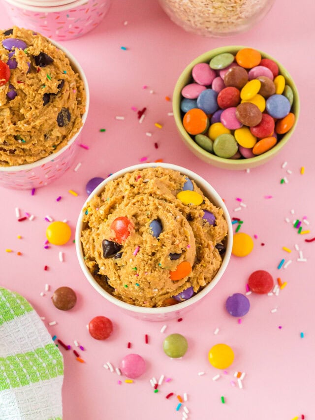 Overhead image of monster cookie dough in cups with candy on the table.