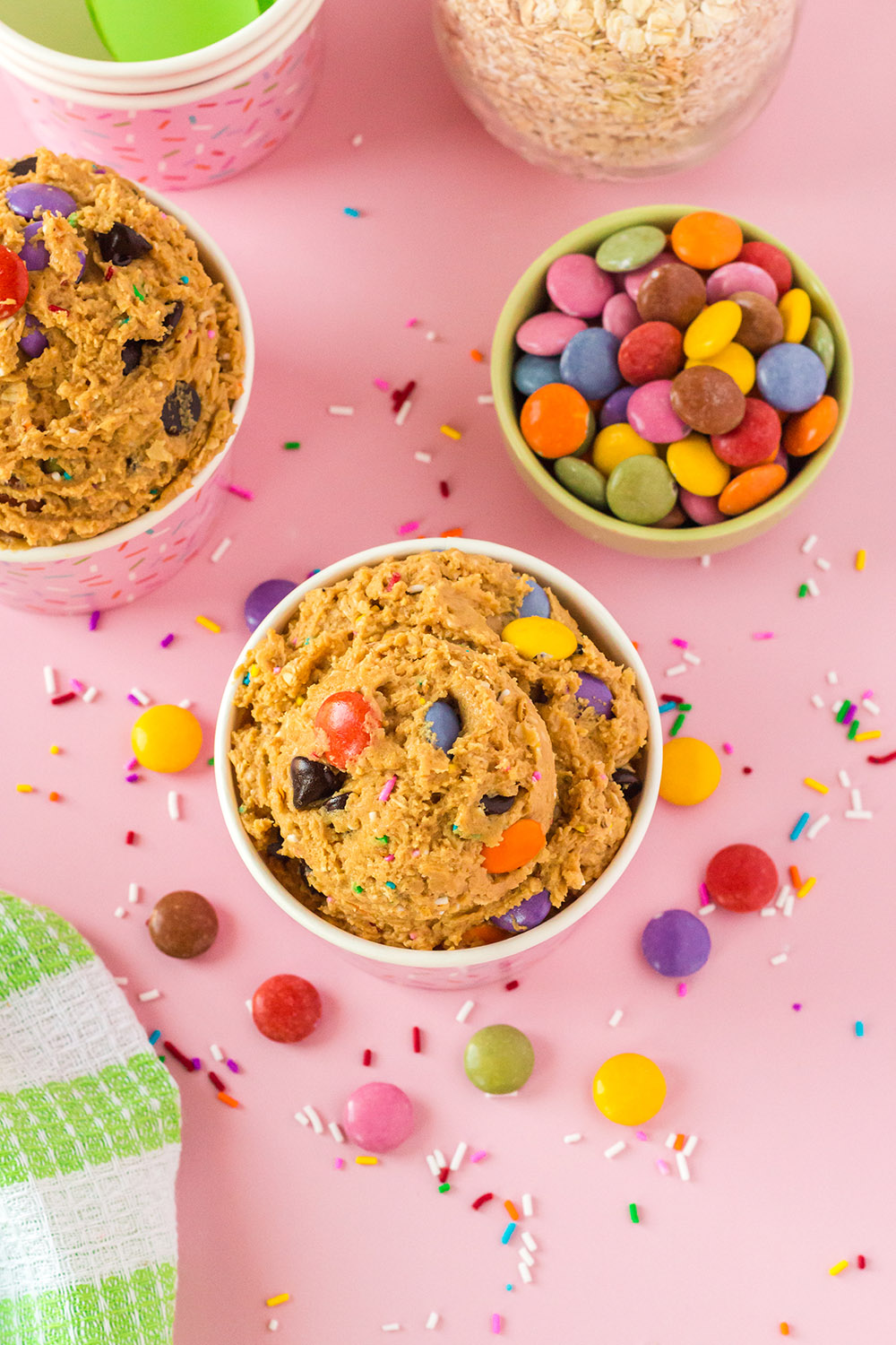 Overhead image of monster cookie dough in cups with candy on the table. 