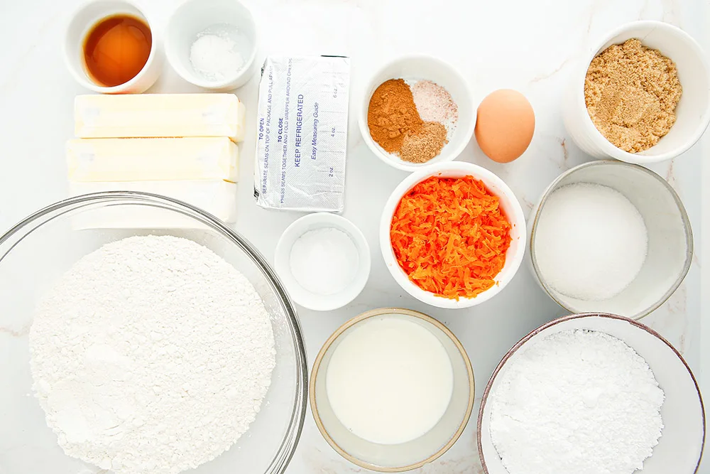Flour, butter, carrots, and other ingredients in bowls. 