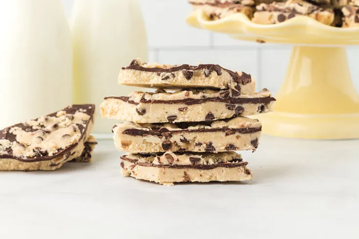 Cookie dough bark candy stacked and on a yellow candy dish.