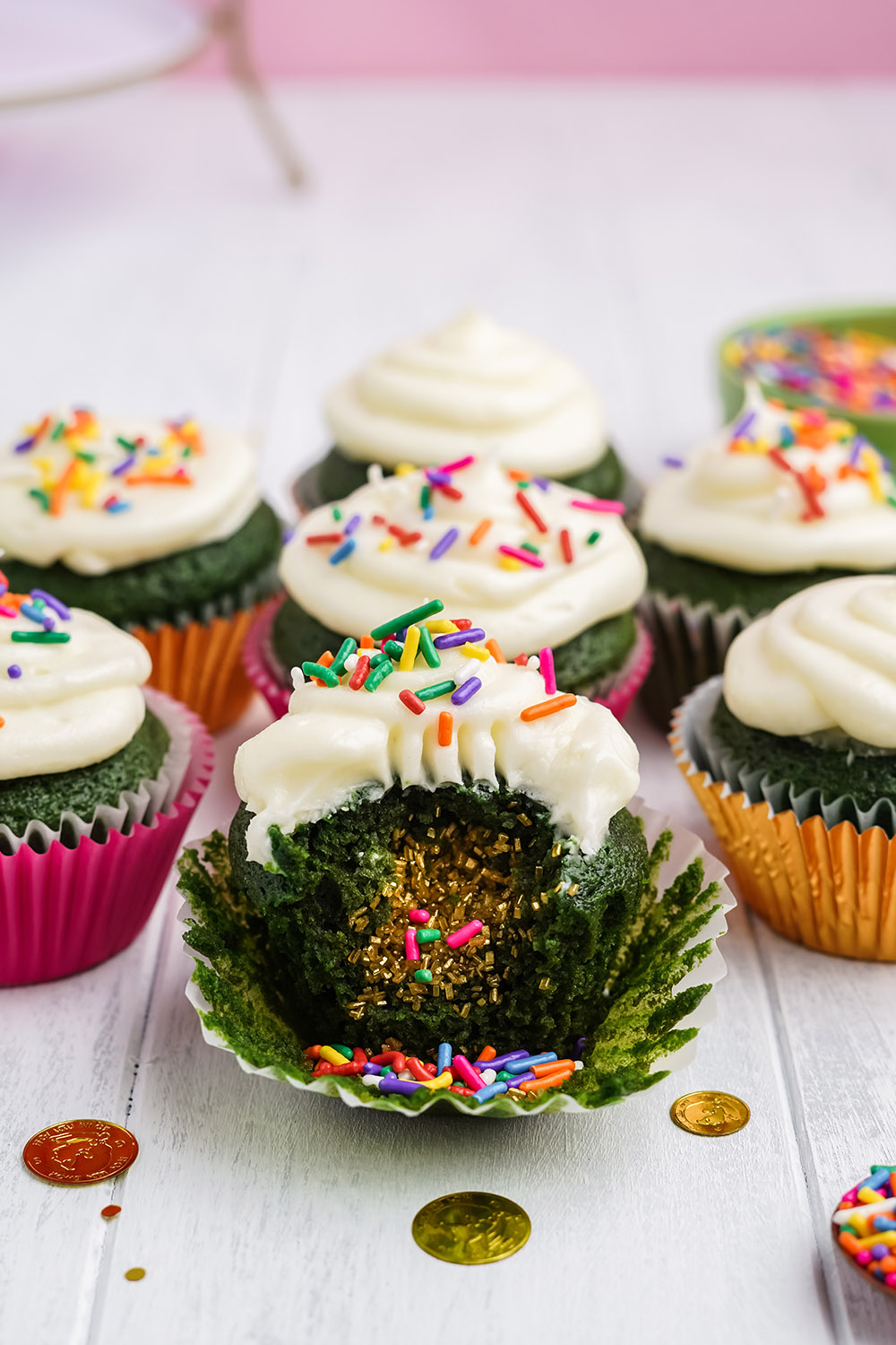 Green cupcakes with white frosting and sprinkles as a surprise filling.