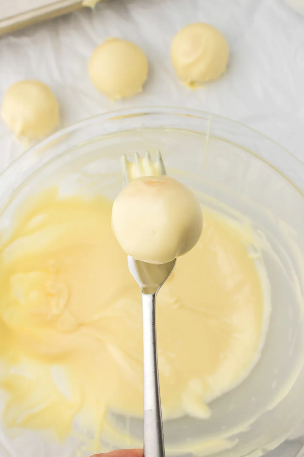 Dipping an oreo ball into coating with a fork.