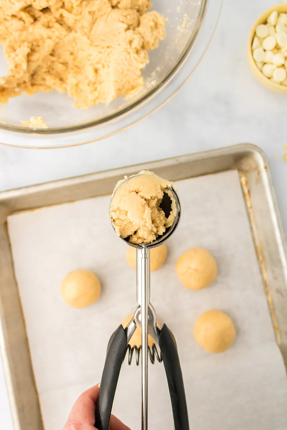 Oreo balls in a cookie scoop above a baking sheet.