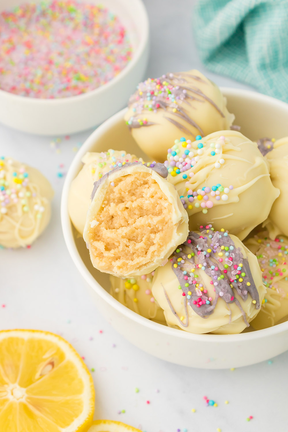 Lemon candy truffles in a bowl with one missing a bite.
