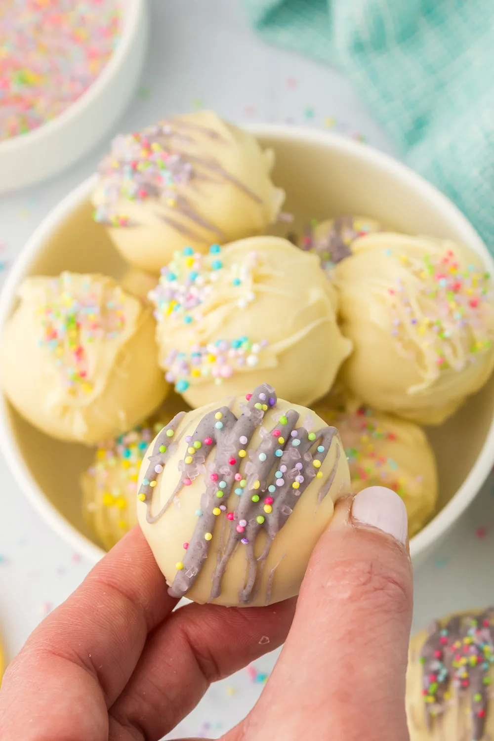 Holding a lemon oreo ball above a bowl of them. 