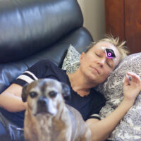 Woman on the couch wearing a Cefaly device for migraine treatments.