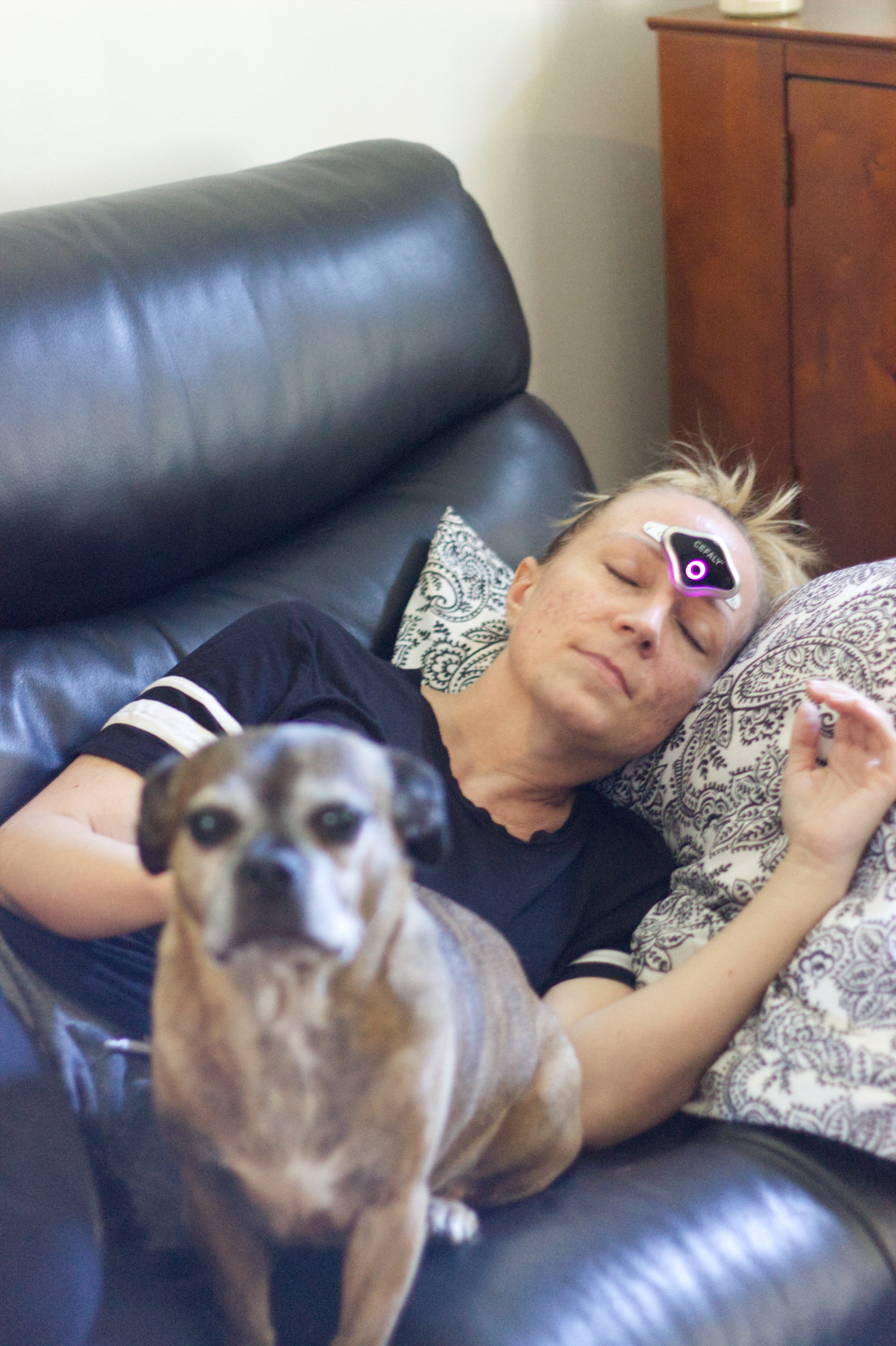 Woman on the couch wearing a Cefaly device for migraine treatments. 