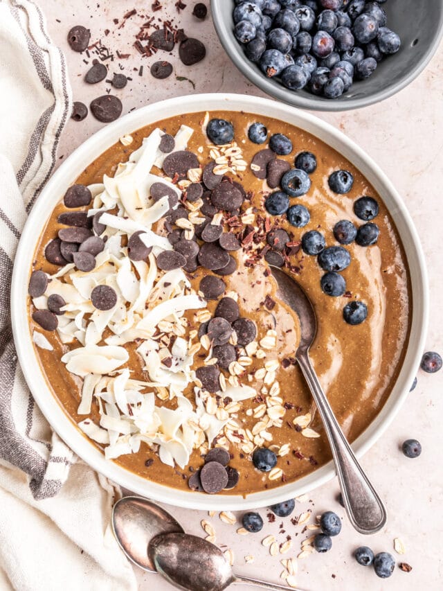 Peppermint mocha smoothie bowl next to a bowl of blueberries.