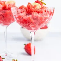 Strawberry granita in a glass with strawberries on the table.