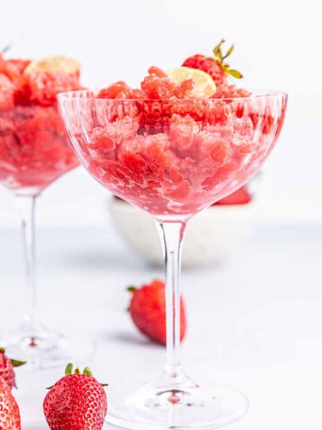 Strawberry granita in a glass with strawberries on the table.