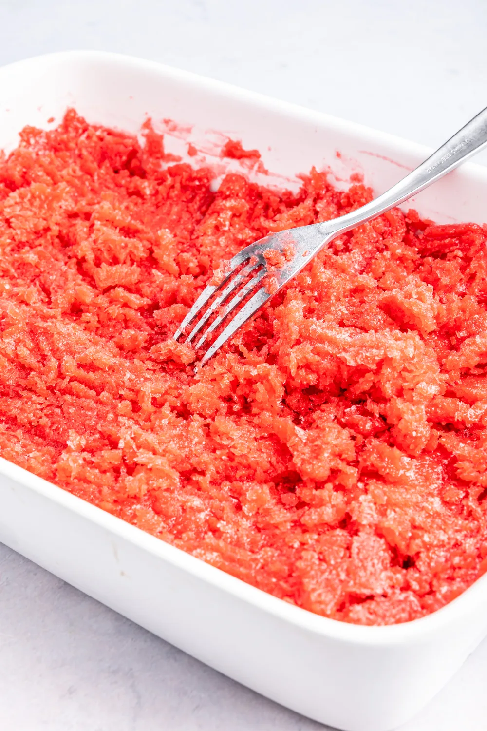 Frozen strawberry lime granita with a fork in it.
