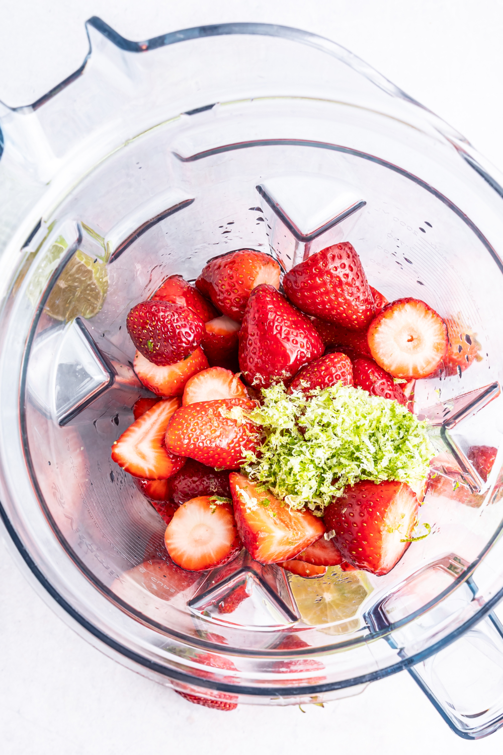 Lime zest on top of strawberries in a blender.