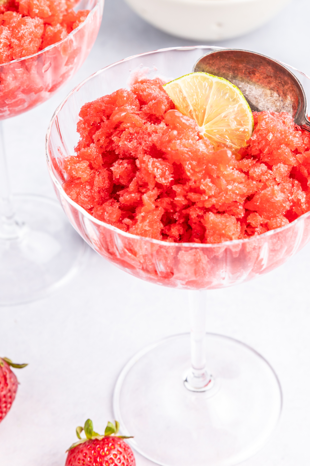 A glass of strawberry granita topped with a slice of lime. 