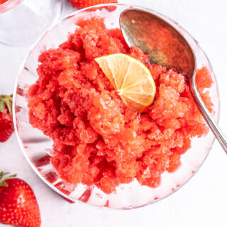 Overhead of strawberry granita topped with a lime slice in a glass.