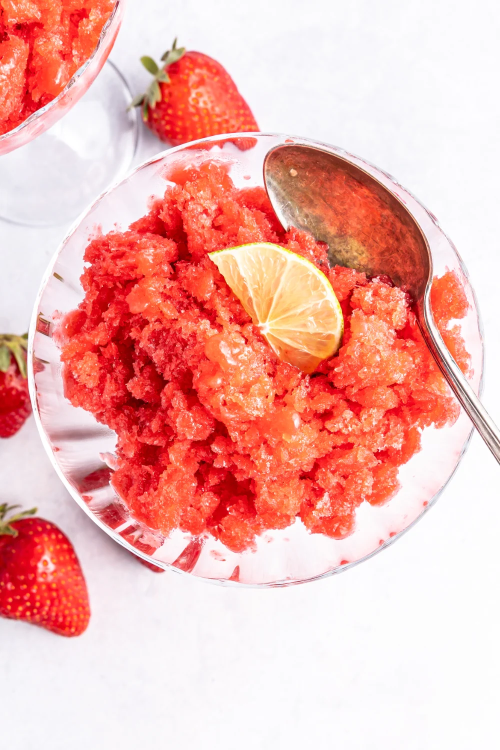 Overhead of strawberry granita topped with a lime slice in a glass. 