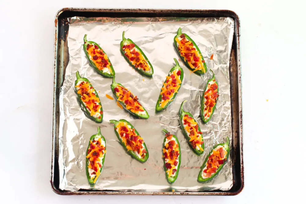 Jalepeno poppers on a baking sheet with foil.