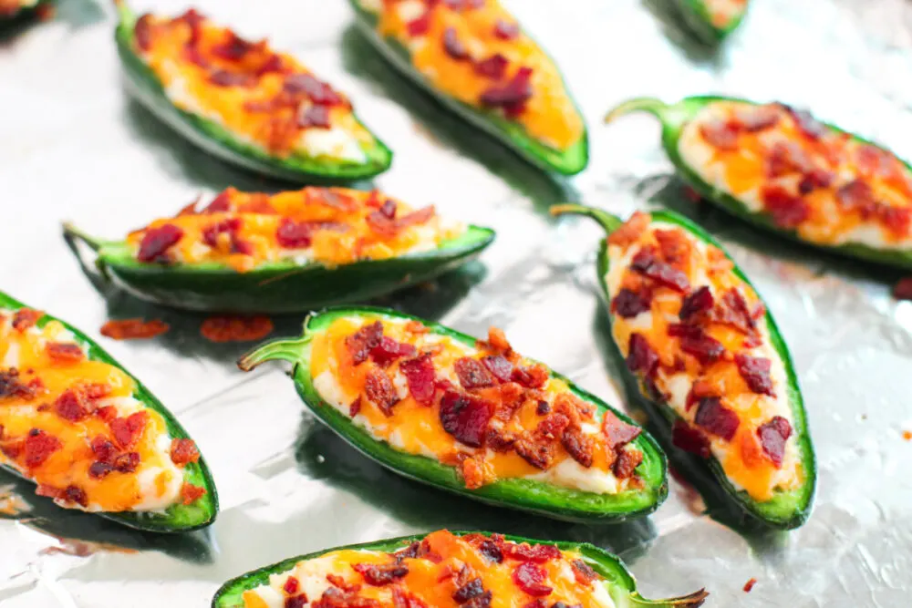Stuffed jalepenos on a foil baking sheet ready for the oven. 