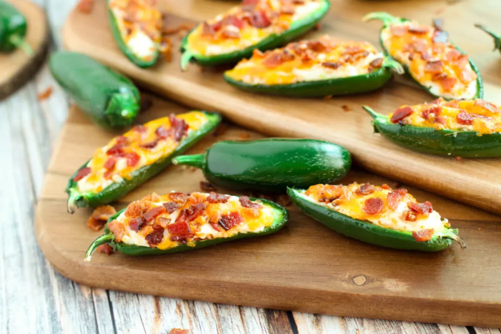 Jalepeno poppers with bacon on a board.