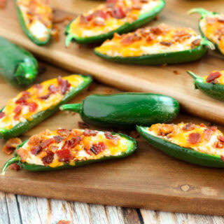 Jalepeno poppers with bacon on a board.