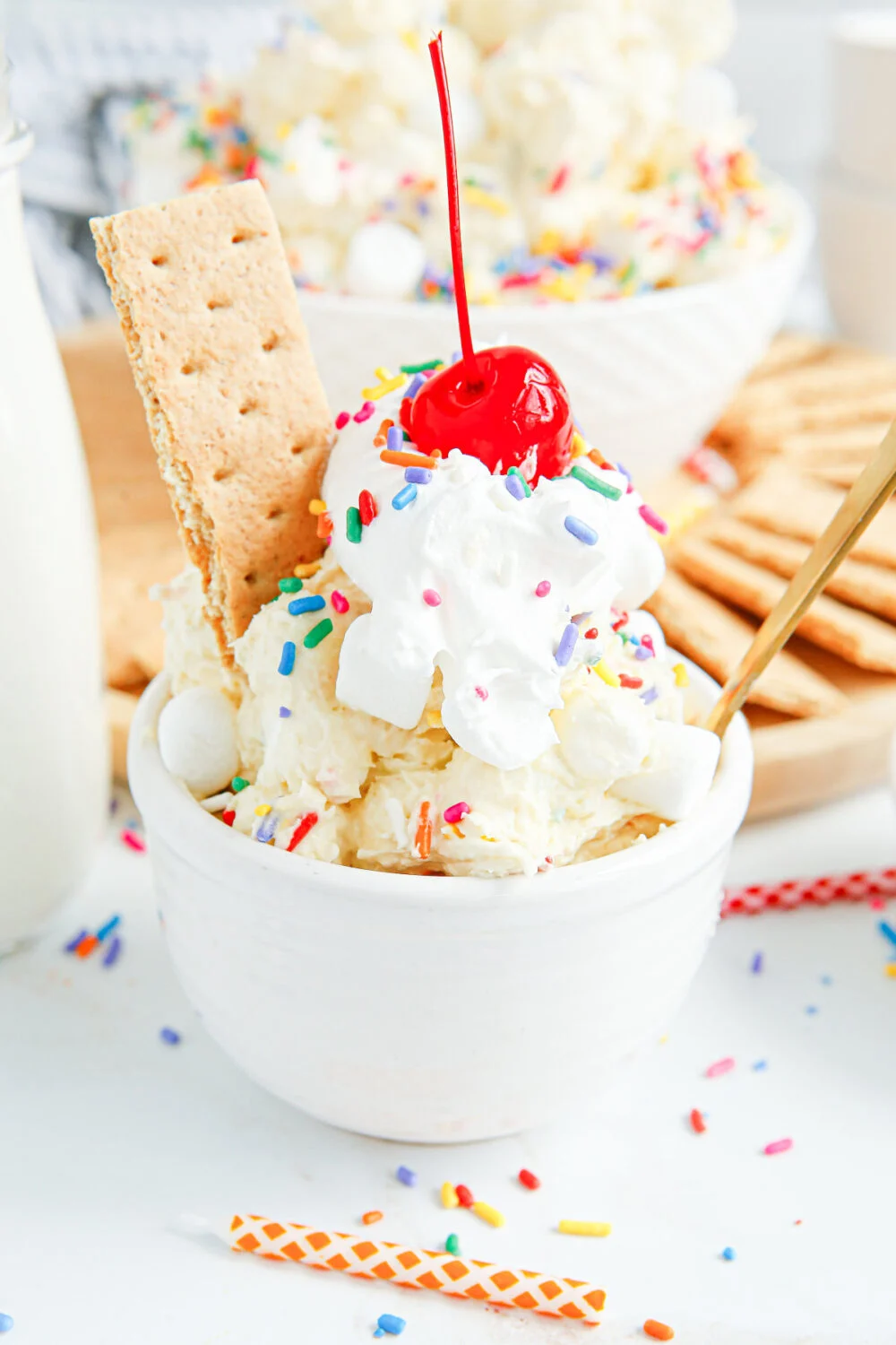 Bowl of fluff salad with a graham cracker and a cherry topping. 