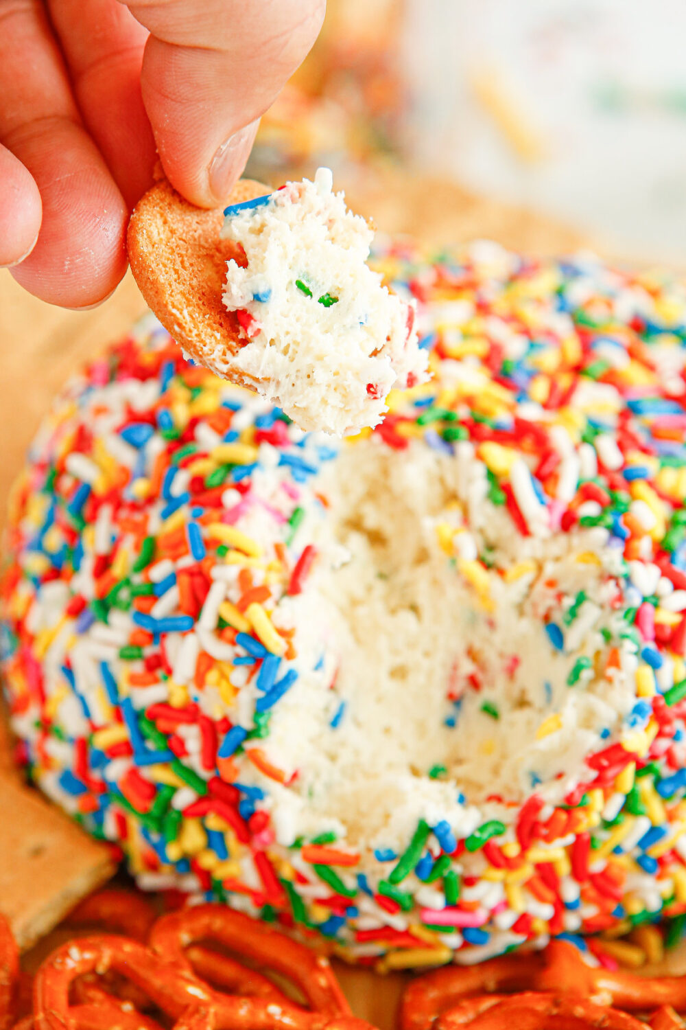 Dipping a cracker into a cheese ball covered in sprinkles. 
