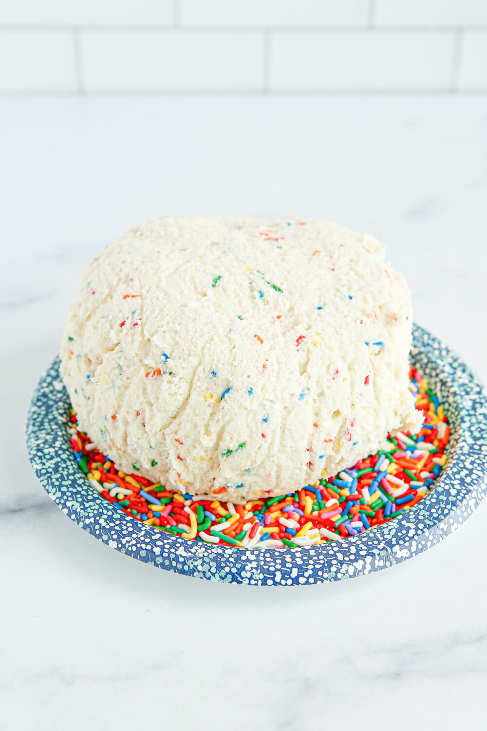 Cheese ball dip on top of sprinkles on a plate. 