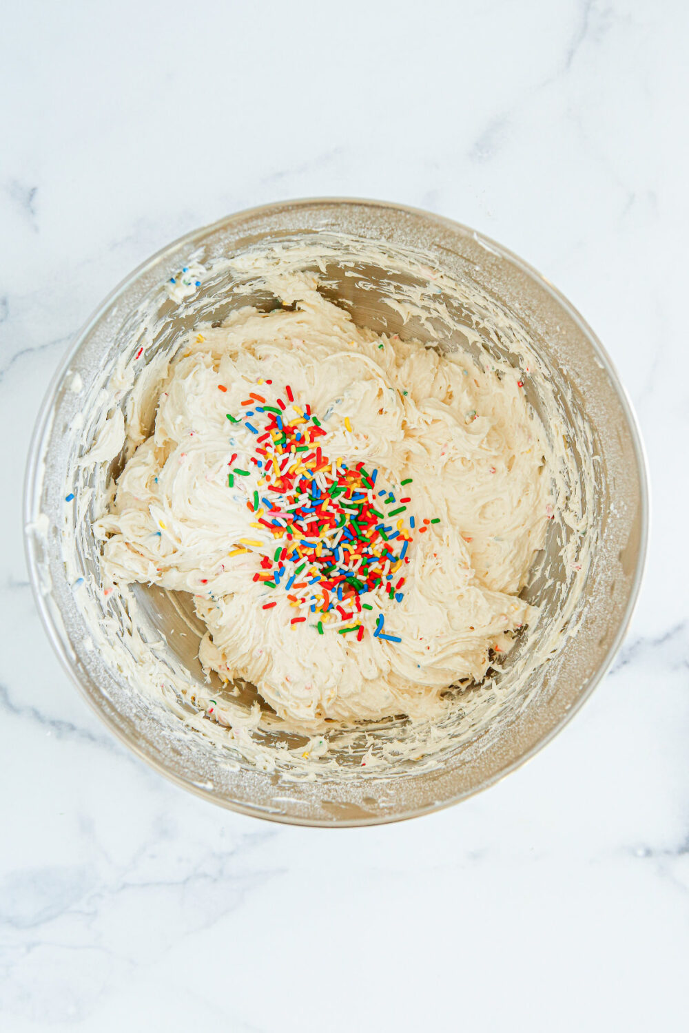 Sprinkles on top of cream cheese mixture in a bowl. 