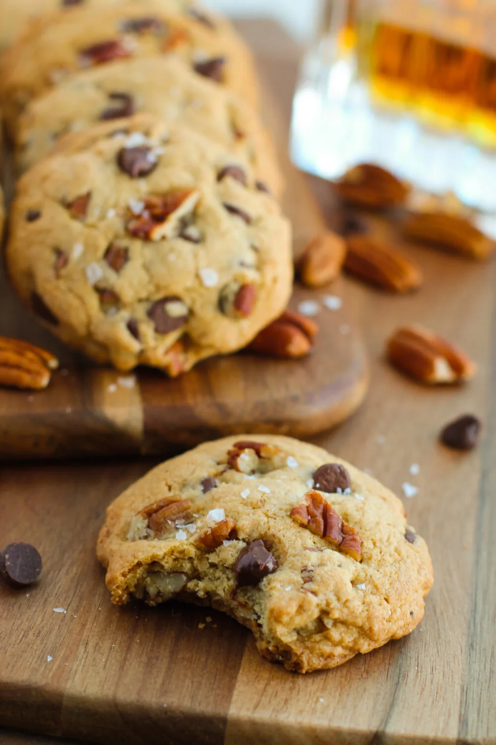 Chocolate chip cookies with pecans and one with a bite missing. 