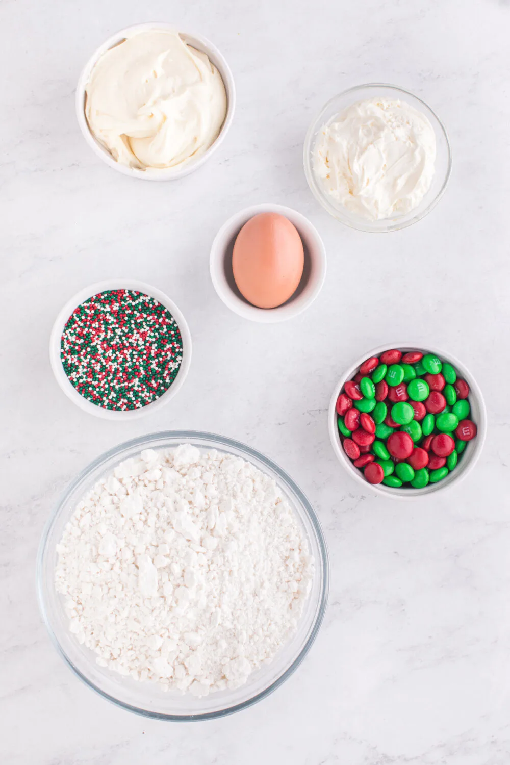 Egg, M&Ms, sprinkles, flour, and other ingredients for sugar cookie pie. 