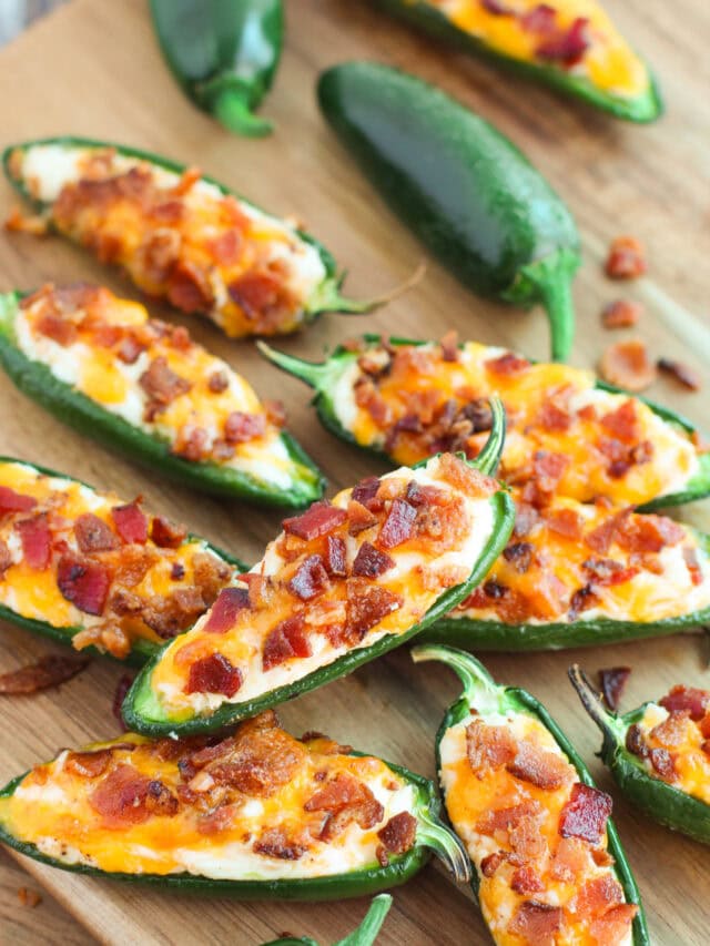 Several bacon jalepeno poppers on a cutting board.