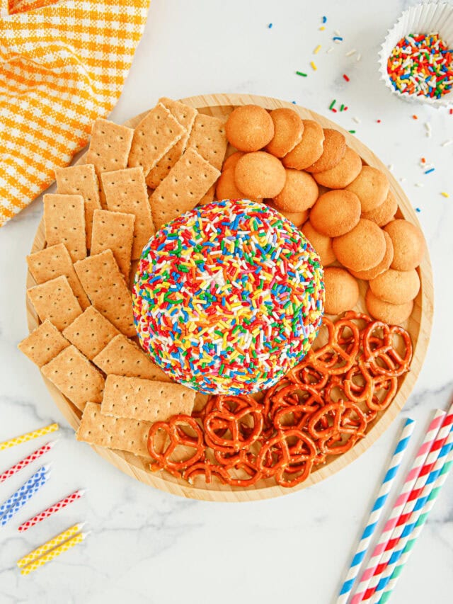 Funfetti cheese ball in the middle of a plate surrounded by pretzels, graham crackers, and nilla wafers.