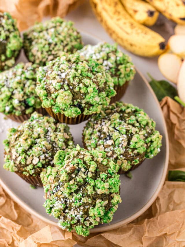 Green muffins stacked on a tray next to bananas.