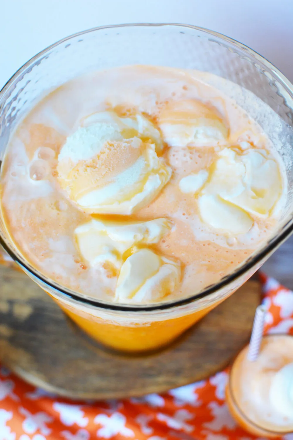 Orange punch with ice cream floating in a pitcher. 