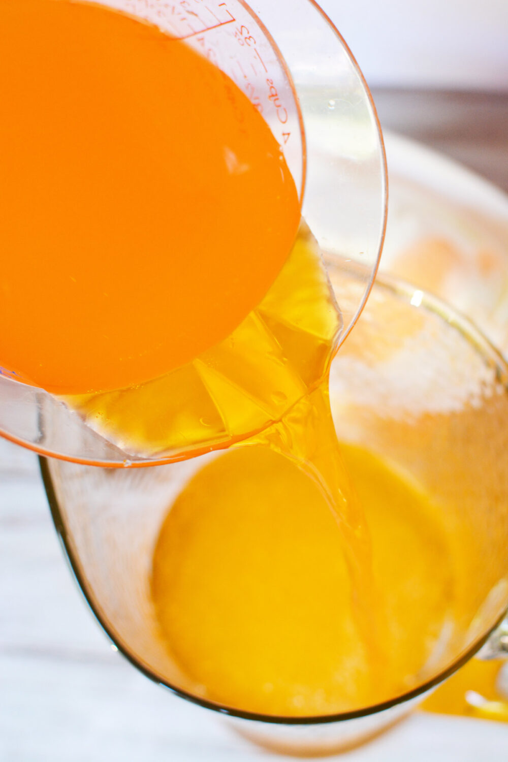 Pouring orange drink into a pitcher. 
