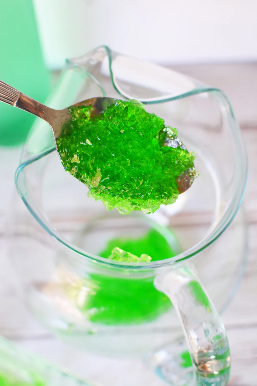 Adding pieces of green jello to a pitcher. 